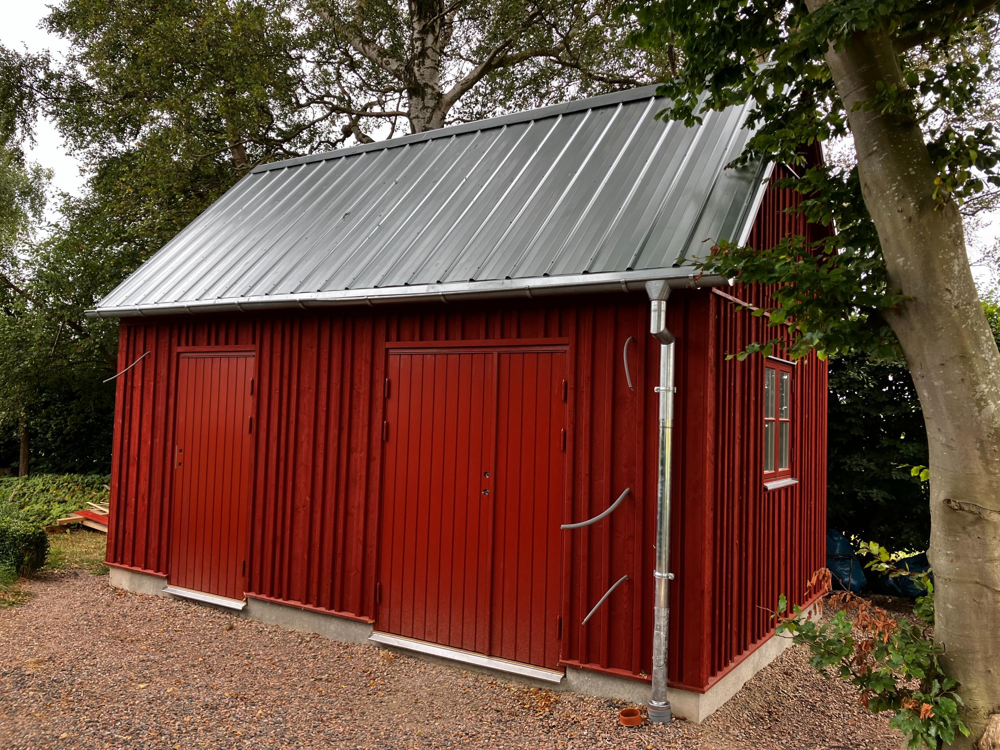 Förråd / snickeri. Faluröd, oregelbunden locklistpanel, cellulosaisolering. Galvad pannplåt.